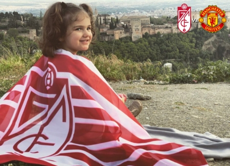 Una muy joven aficionada rojiblanca luce contenta la bandera del Granada ante la Alhambra (FRAN CALVO)