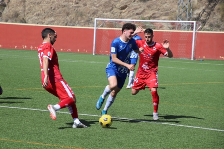 Un jugador del Atlético Monachil entre dos jugadores del Rincón (MANU LÓPEZ)