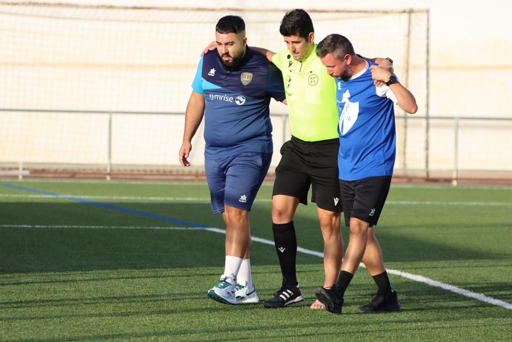 El árbitro López Romero se apoya en miembros del cuerpo técnico de Huétor Vega y Arenas tras caer lesionado (JOSÉ ANDRÉS FERNÁNDEZ / ARENAS DE ARMILLA) El árbitro López Romero se apoya en miembros del cuerpo técnico de Huétor Vega y Arenas tras caer lesionado (JOSÉ ANDRÉS FERNÁNDEZ / ARENAS DE ARMILLA)