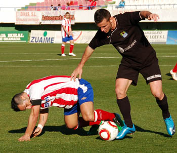 Un jugador visitante intenta arrebatarle el balón a un local