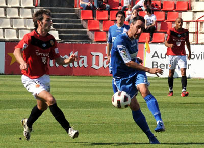 Abel Gómez golpea el balón ante un jugador del Nástic (J. M. BALDOMERO)