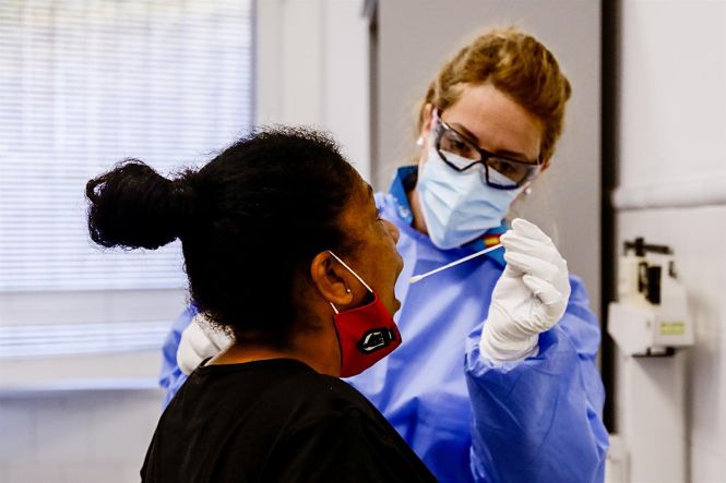 Una trabajadora sanitaria protegida realiza un test a una mujer (RICARDO RUBIO - EUROPA PRESS)